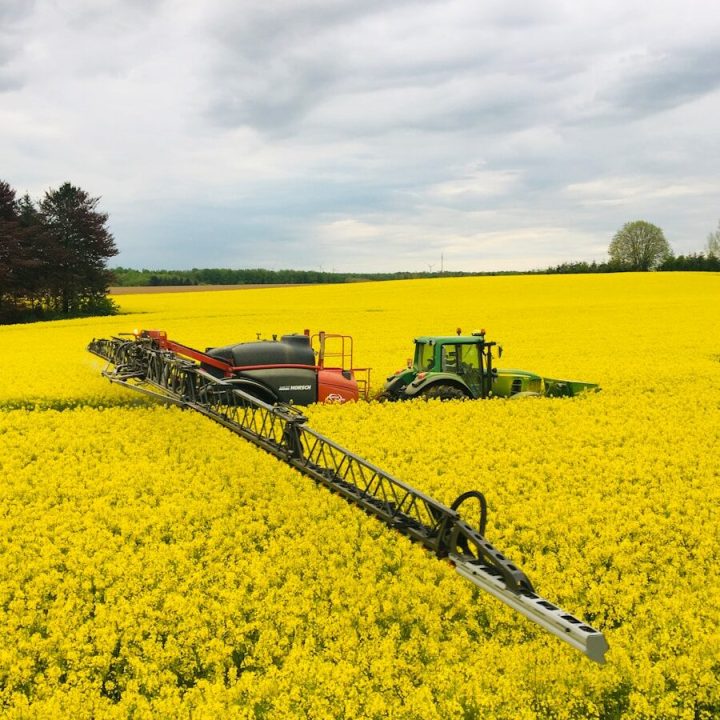 green tractor on yellow flower field during daytime
